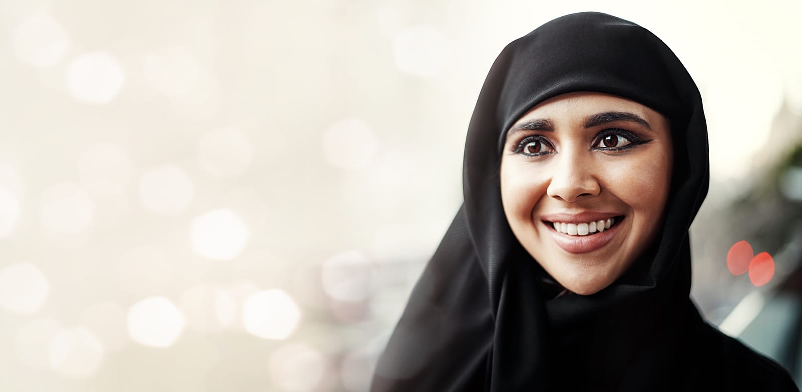 This enchanting photo features a joyful Muslim woman, embodying the spirit of adventure amidst a breathtaking outdoor setting. With the soft bokeh illuminating her face, she reflects the happiness that comes with spiritual exploration during Ramadan and Hajj.